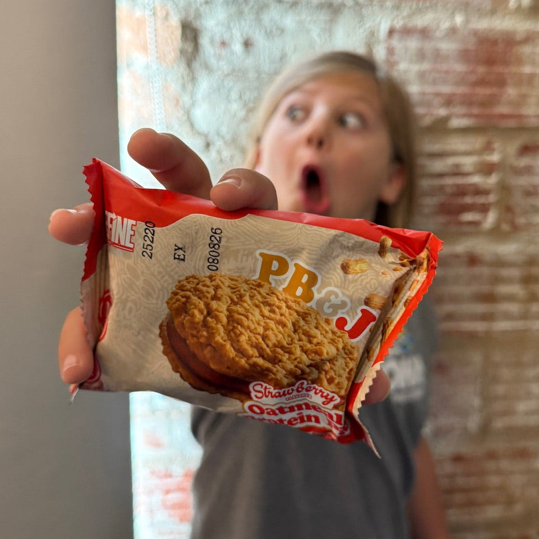 Person holding a PB&J cookie package with a surprised expression